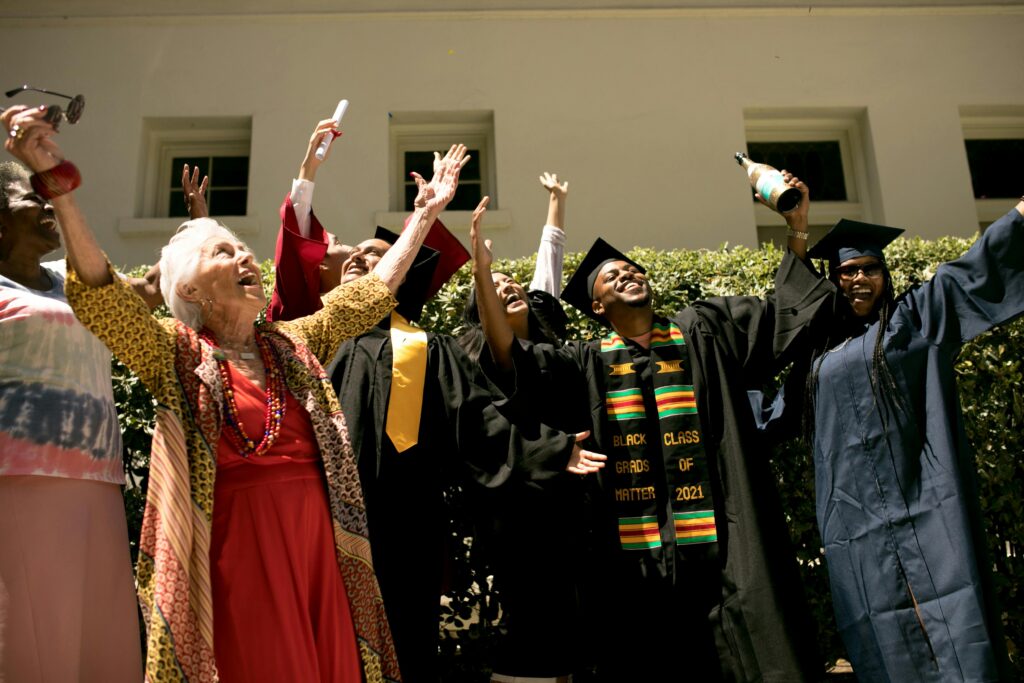 Diverse group celebrating graduation outdoors with family and friends.